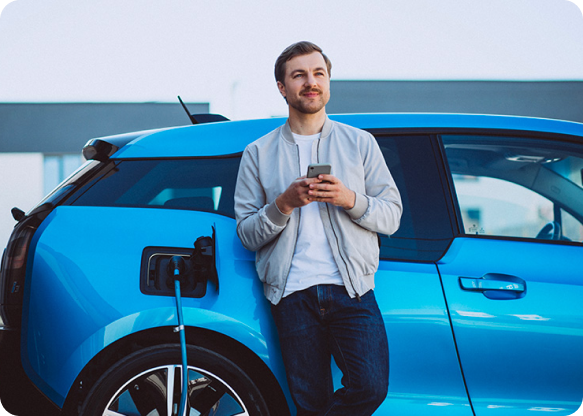 giovane con celllulare mentre  ricarica auto elettrica
